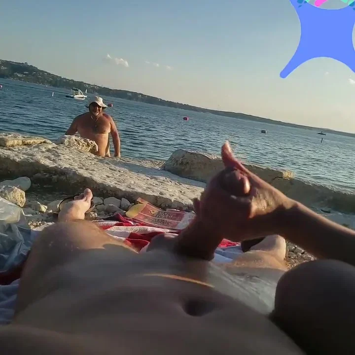 On a nude beach the wife stokes my cock while a voyuer watches
