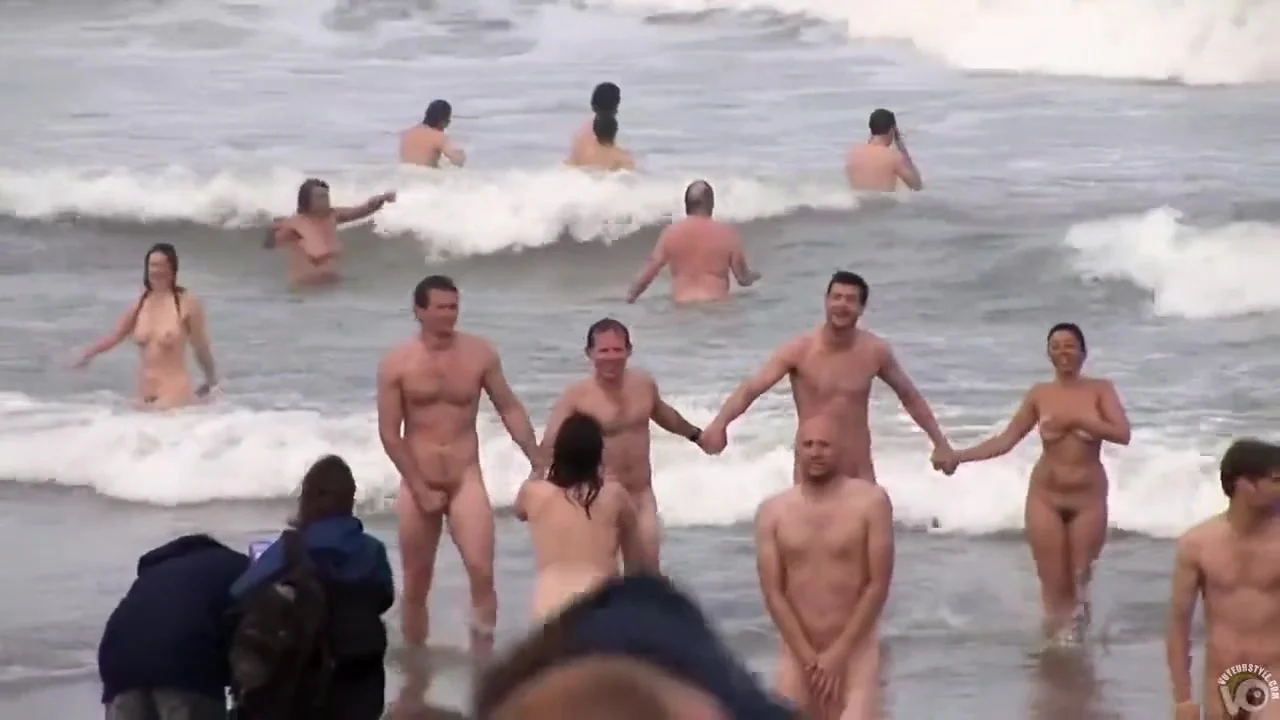Hundreds of nudist people running into the sea naked