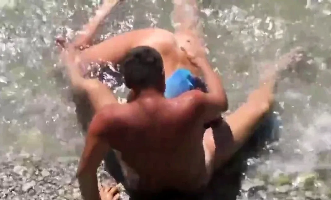 Girl sucks dick her boyfriend in the surf at a public beach